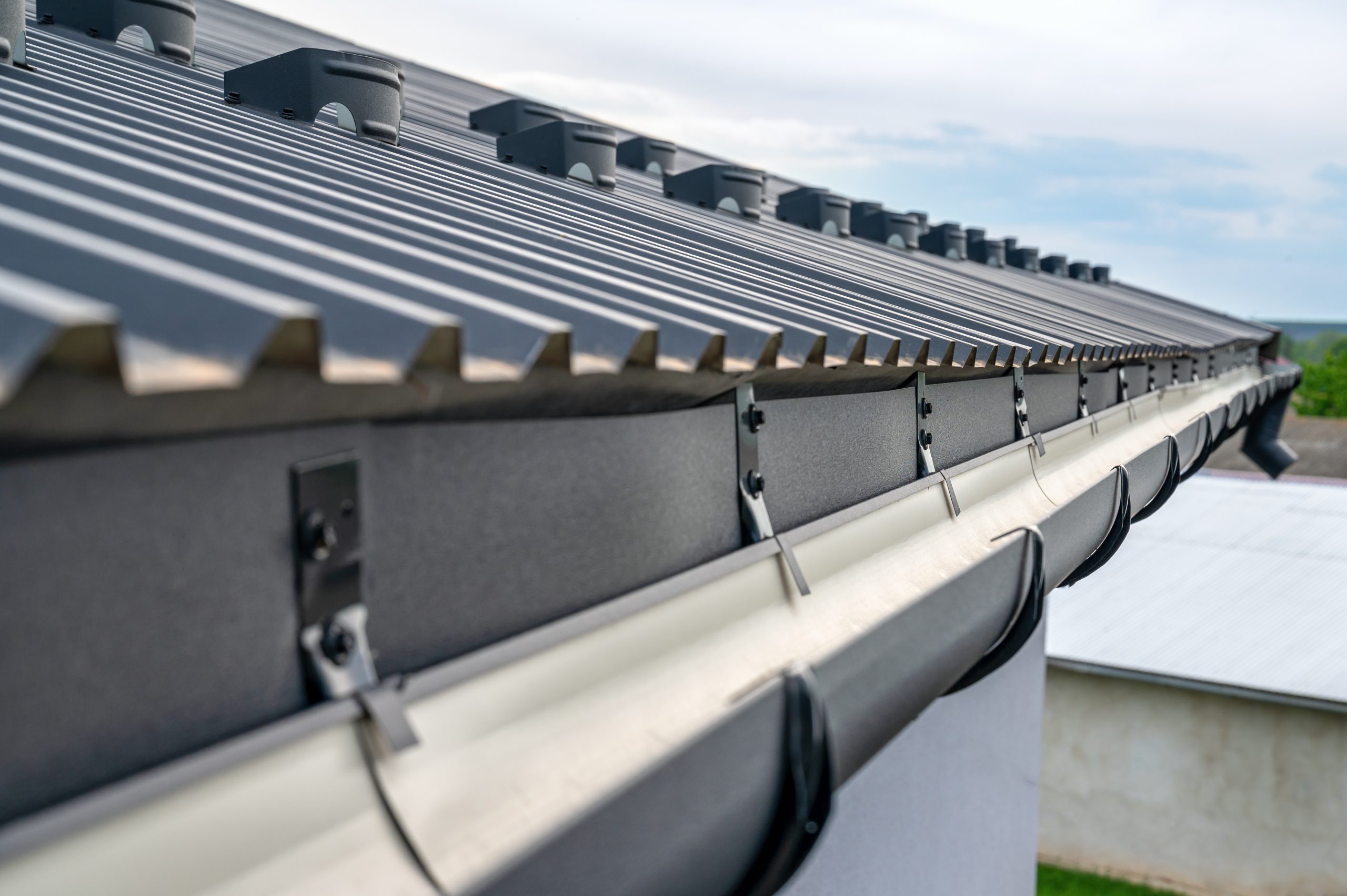 Close-up of a metal roof with a rain gutter system attached to the edge of a building.